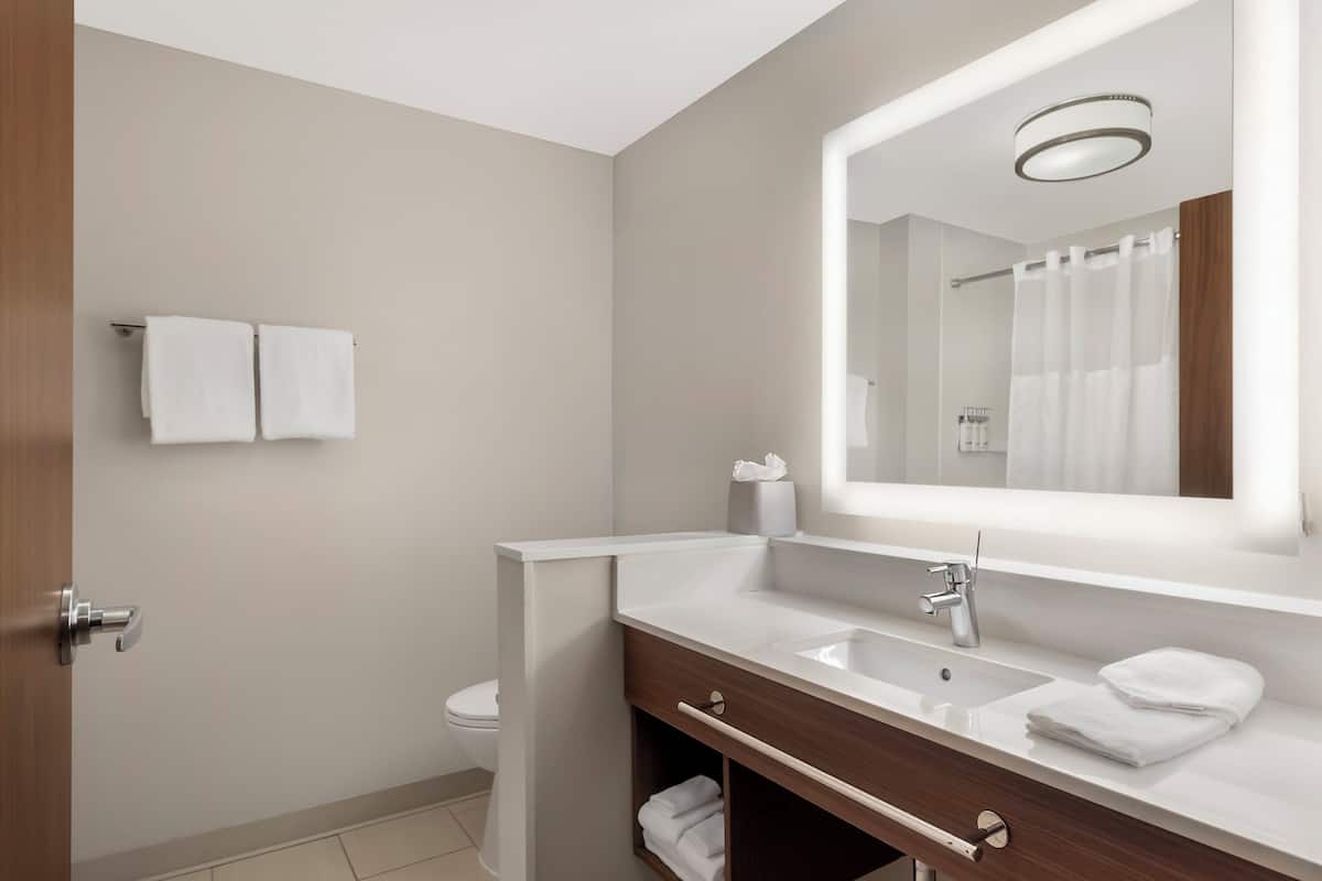 A modern bathroom with a white sink, mirror, and towel rack.