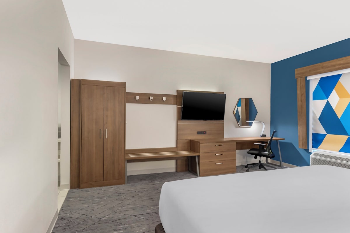 Une chambre d’hôtel comprenant un lit, un bureau avec un ordinateur, une télévision et une armoire.