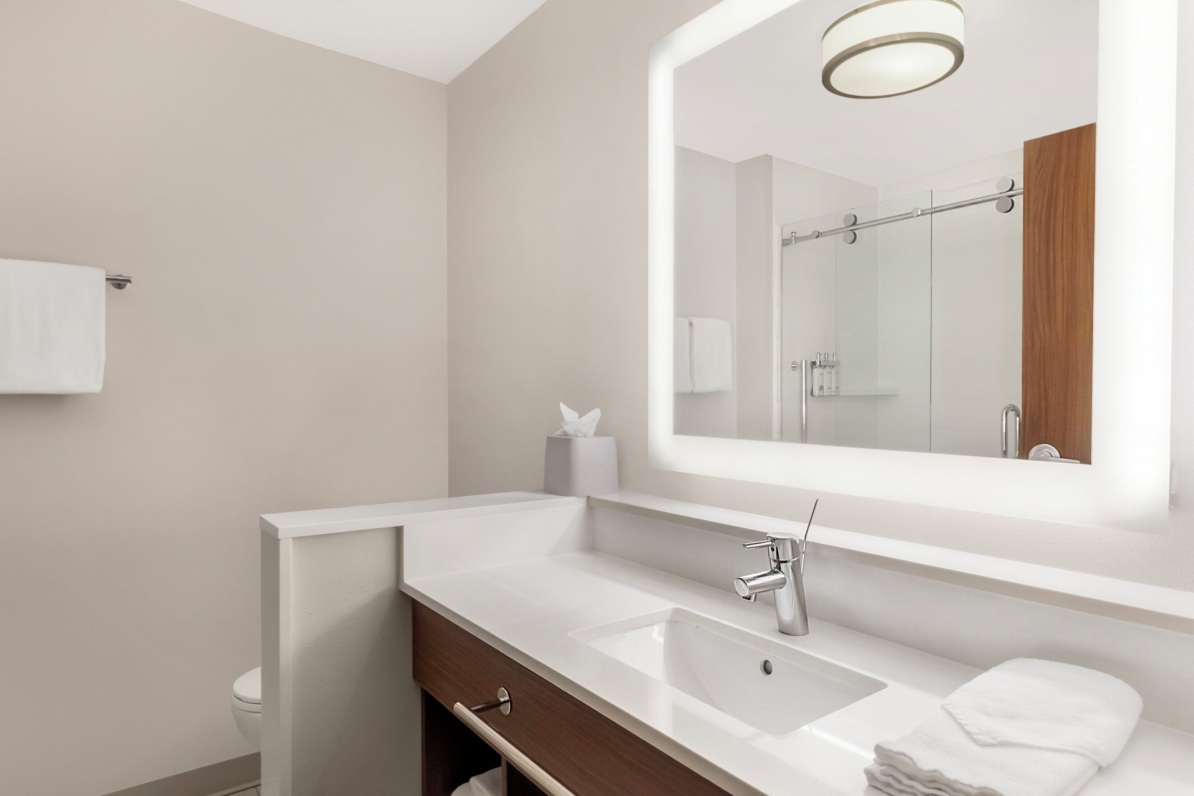 Un baño moderno con un espejo grande, un lavamanos y un inodoro.