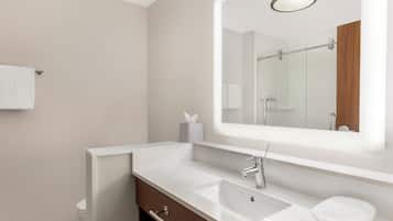 Un baño moderno con un espejo grande, un lavamanos y un inodoro.