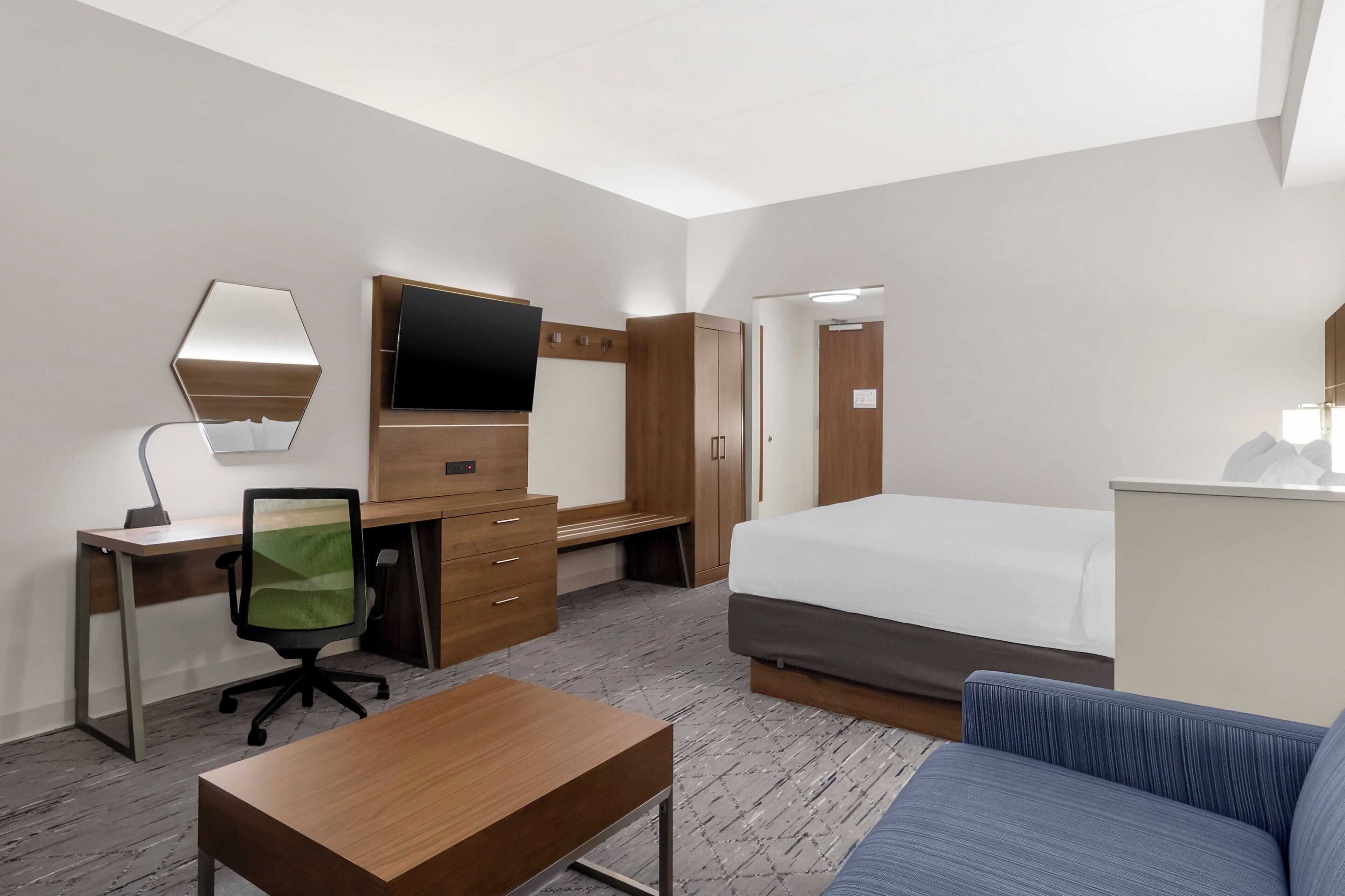 Ein Hotelzimmer mit einem Bett, einem Schreibtisch mit Stuhl, einem Fernseher und einem Kleiderschrank.