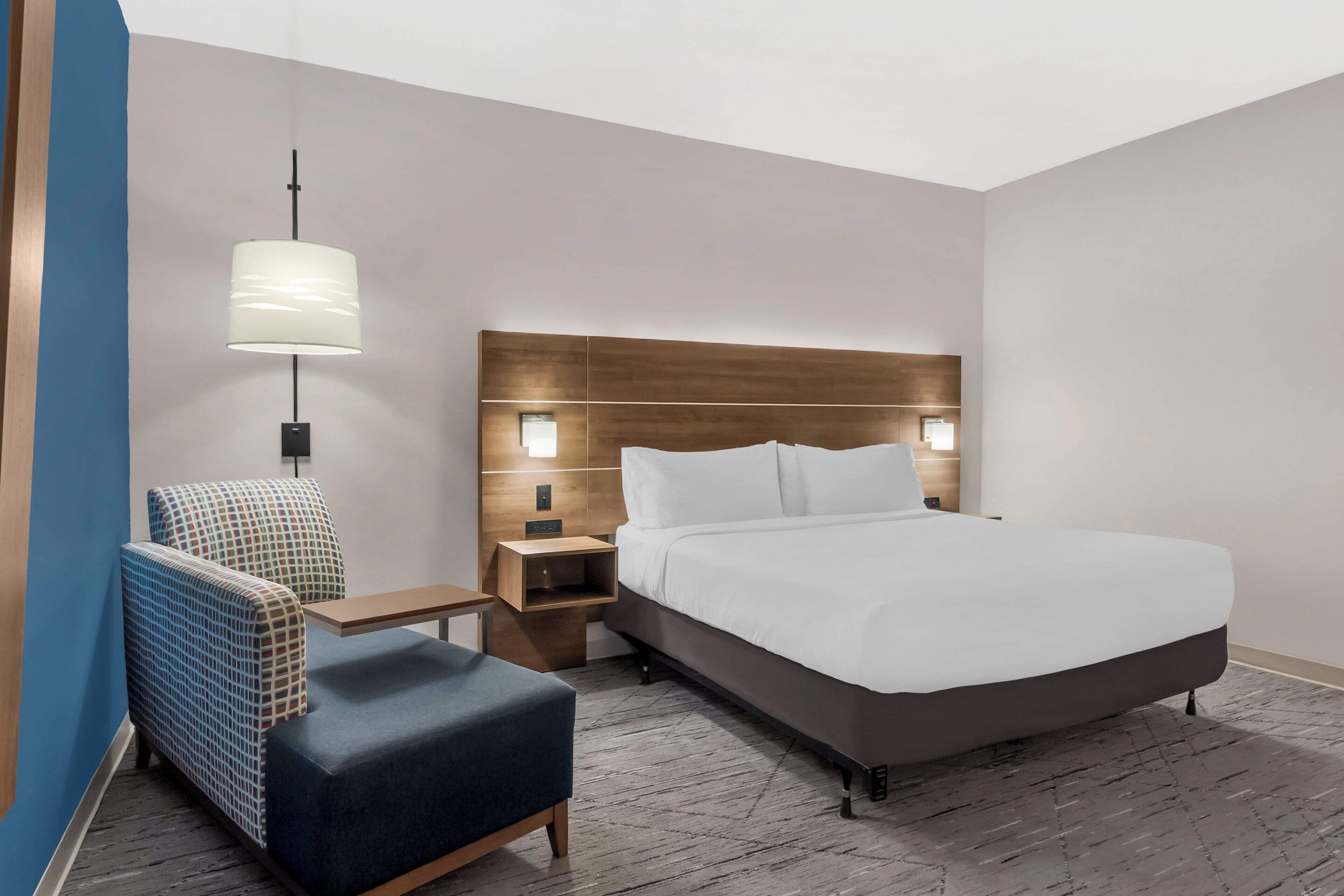 Ein Hotelzimmer mit Bett, Stuhl, Nachttisch und Lampe.