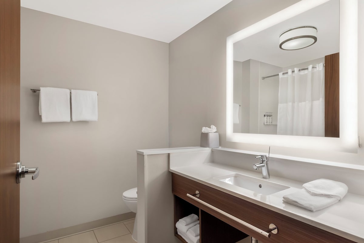 Une salle de bain moderne avec un lavabo blanc, un miroir et un porte-serviettes.