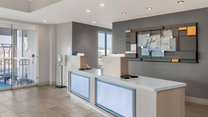 A hotel reception area with a modern design, featuring a reception desk, a glass door entrance, and a wall-mounted sign. - Holiday Inn Express Spring Hill by IHG (Spring Hill)