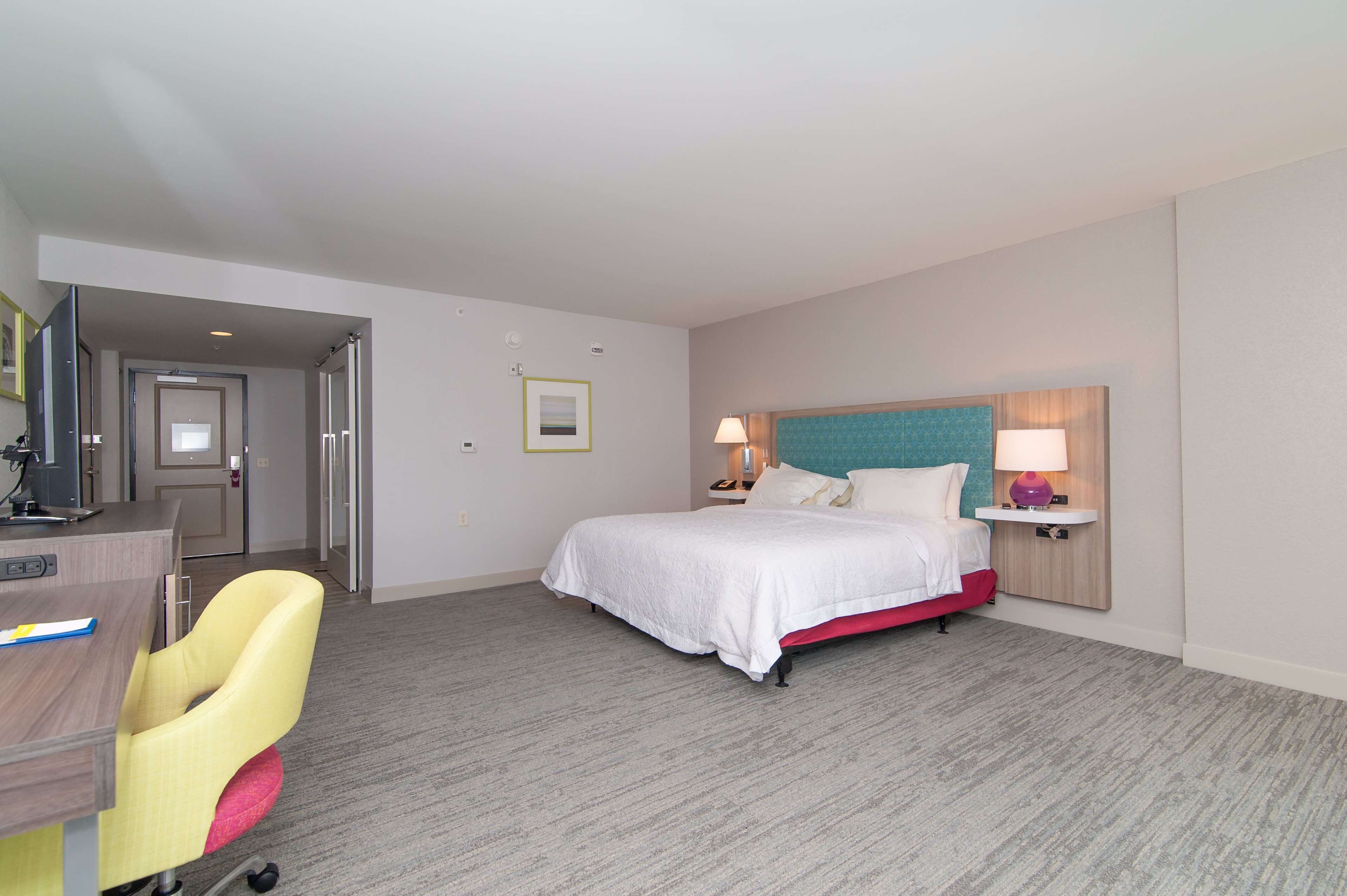 Una habitación de hotel con cama, mesitas de noche, escritorio y silla.