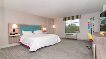 A hotel room with a bed, bedside lamps, a desk, a chair, and a window with a view.
