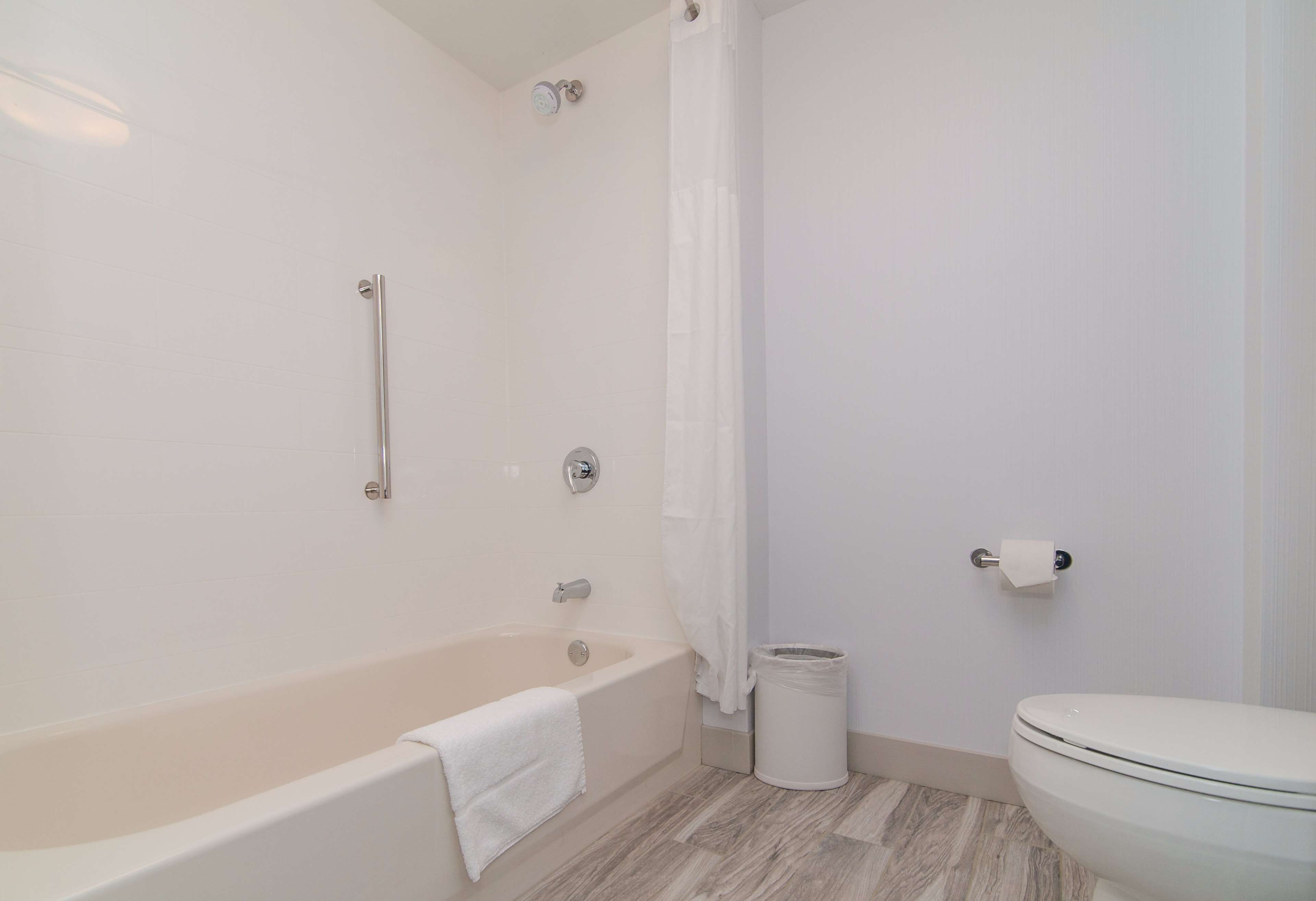 A bathroom with a bathtub, a toilet, and a trash can.