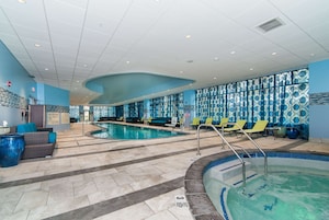 Un área de piscina interior con sillones de descanso, una zona de estar junto a la piscina y un cartel que indica prohibido bucear.