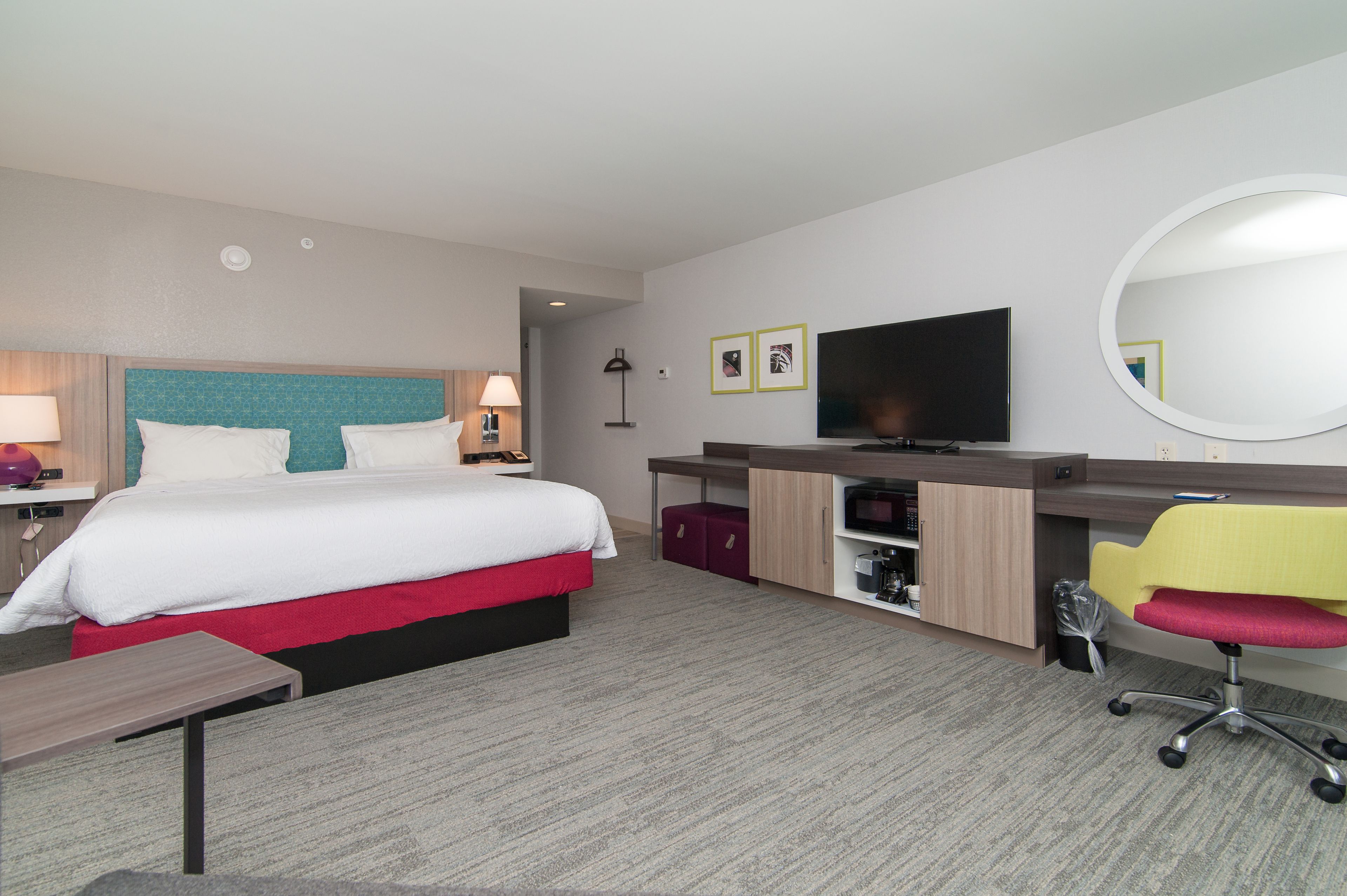 A hotel room with a bed, desk, chair, TV, and storage cabinets.