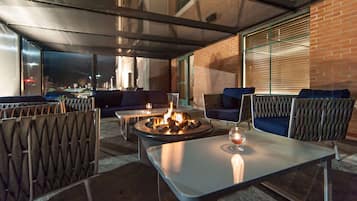 An outdoor seating area with a fire pit, cushioned seating, and a table.