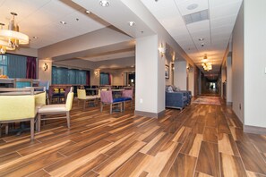 Un hall de hotel con suelo de madera, zonas de estar y un pasillo que conduce a otras habitaciones.
