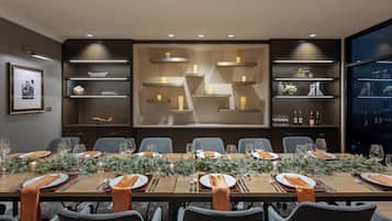 A conference room with a long table set for a meeting, surrounded by chairs.