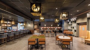 Un restaurante moderno con asientos de bar, mesas redondas y faroles decorativos colgantes.