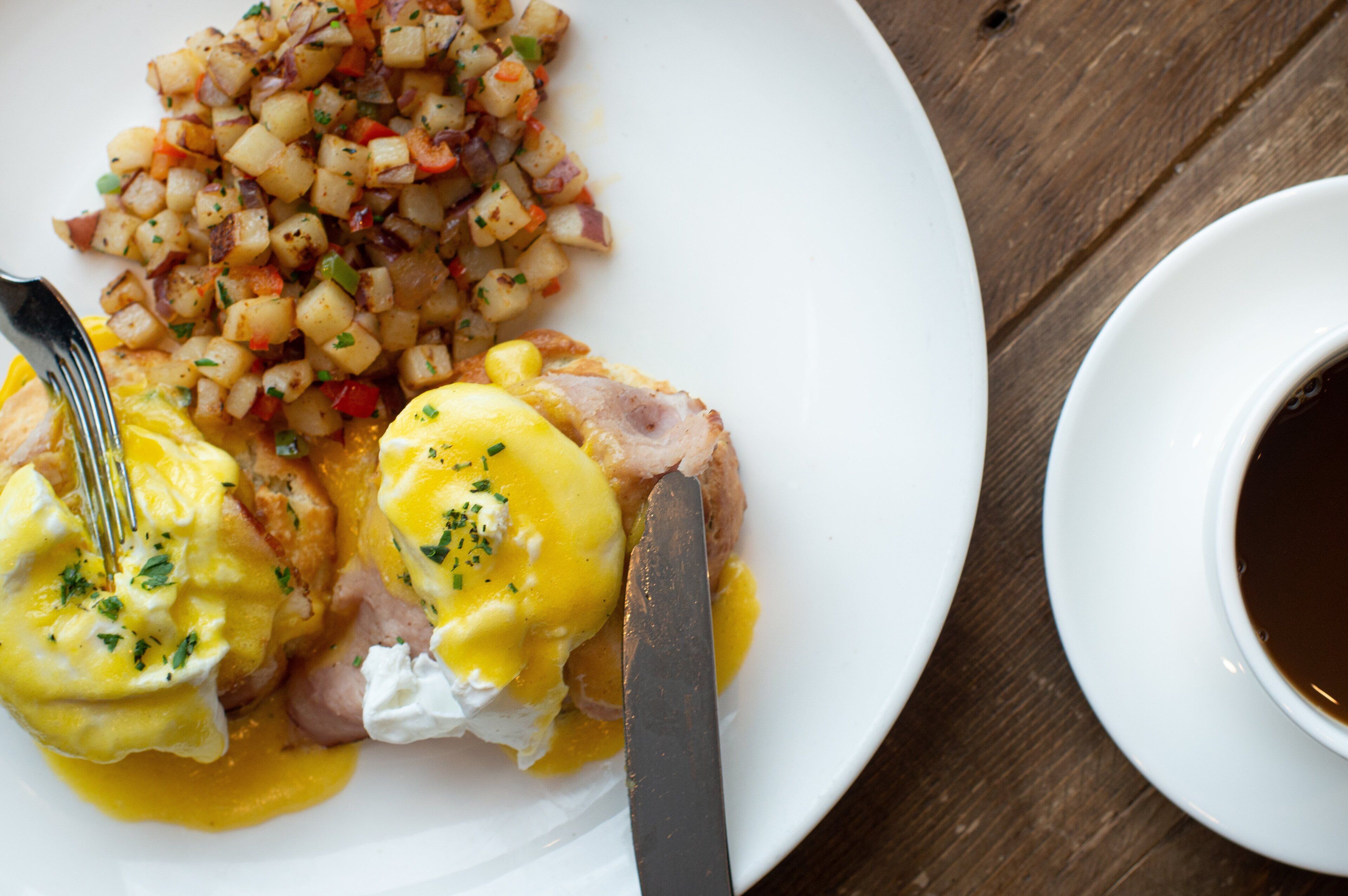 Un plato con huevos Benedict y una guarnición de vegetales picados.