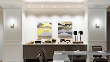 Une salle de conférence avec une longue table, des chaises et deux tableaux accrochés au mur.