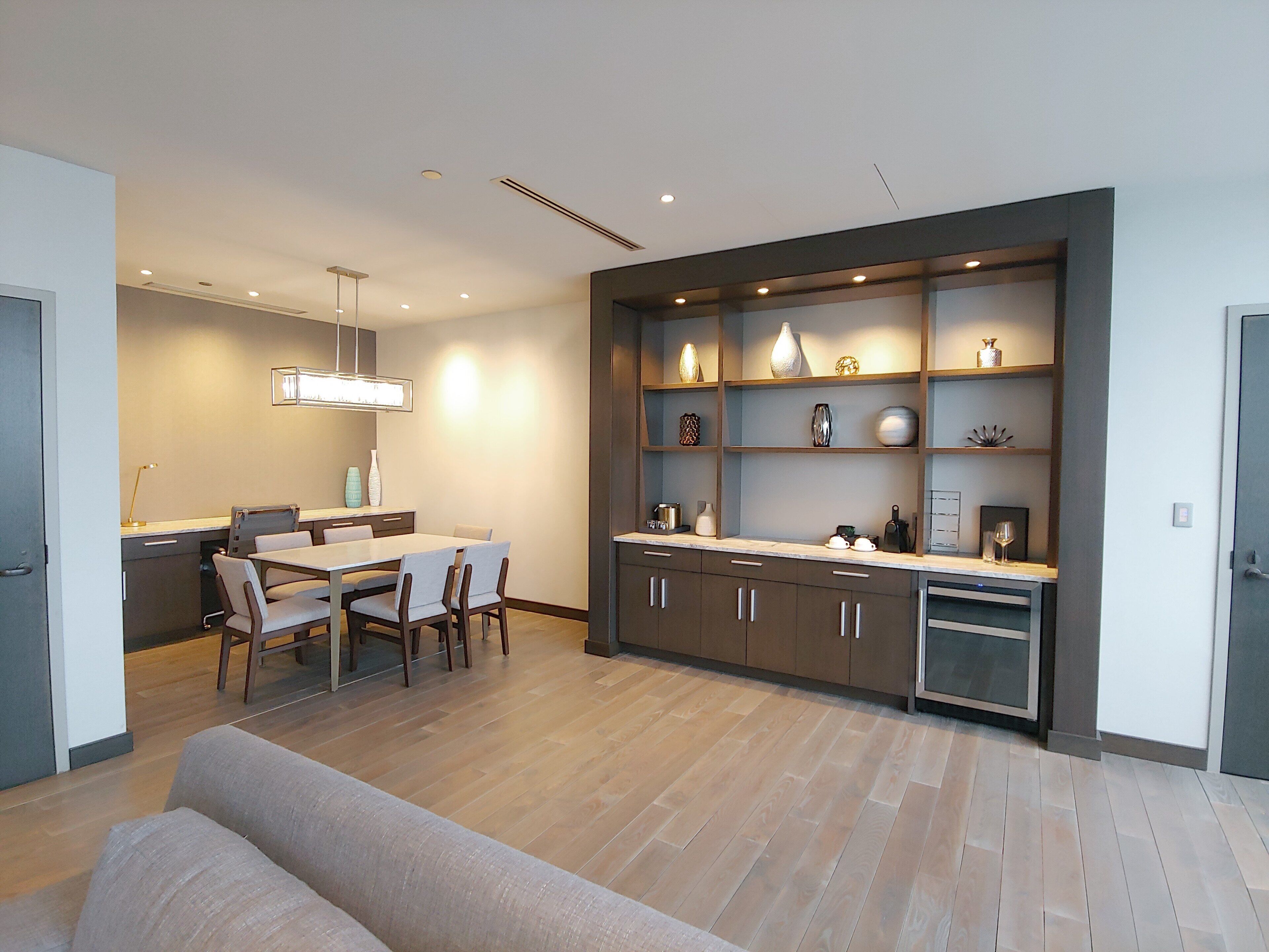 A modern kitchen with a dining area, wooden cabinets, and a built-in bookshelf.