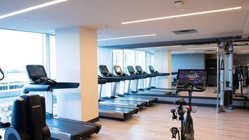 Une salle de sport équipée de tapis de course, de vélos d’exercice et d’appareils de musculation.