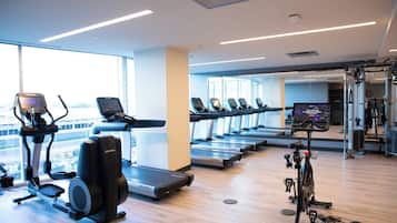 Un gimnasio con cintas de correr, elípticas y una bicicleta estática.