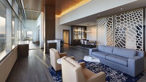 A modern hotel lobby with a seating area, a dining space, and a kitchen visible through glass walls. - InterContinental Minneapolis - St. Paul Airport by IHG (Minneapolis)