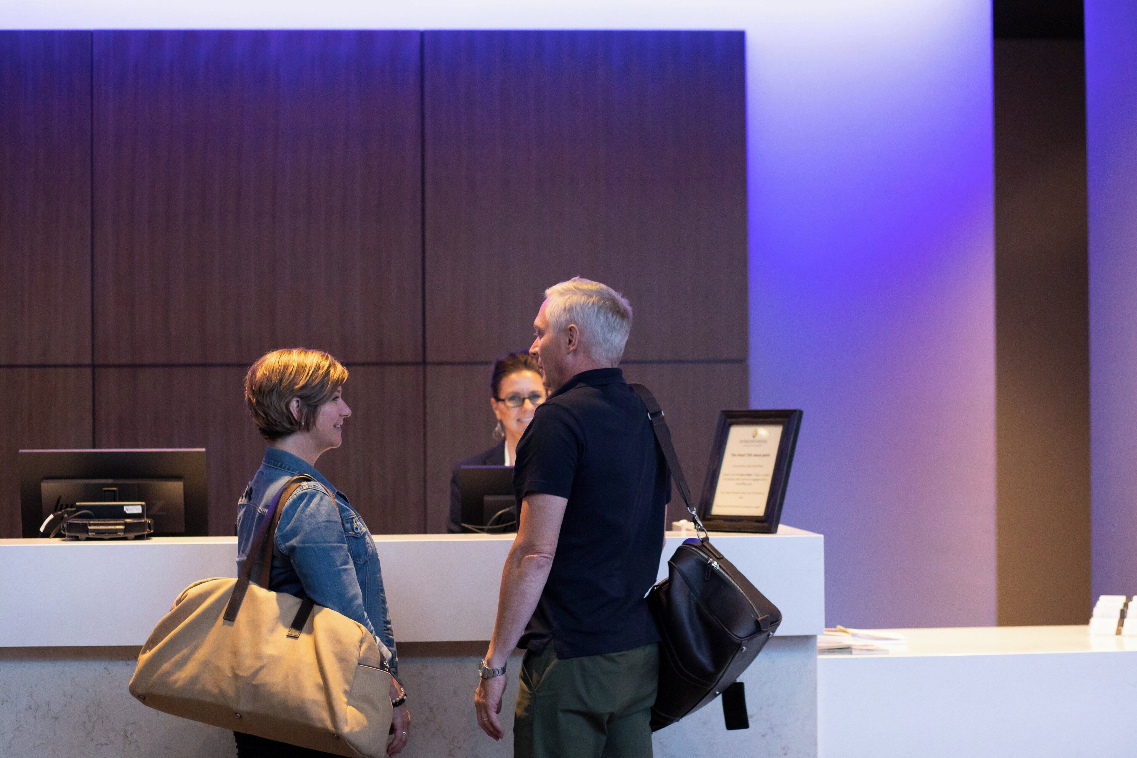 A reception desk with a framed certificate or award, a computer, and a person standing behind it.