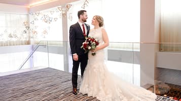 A couple on a balcony with a view of a modern interior, geometric wall art, and a patterned carpet.