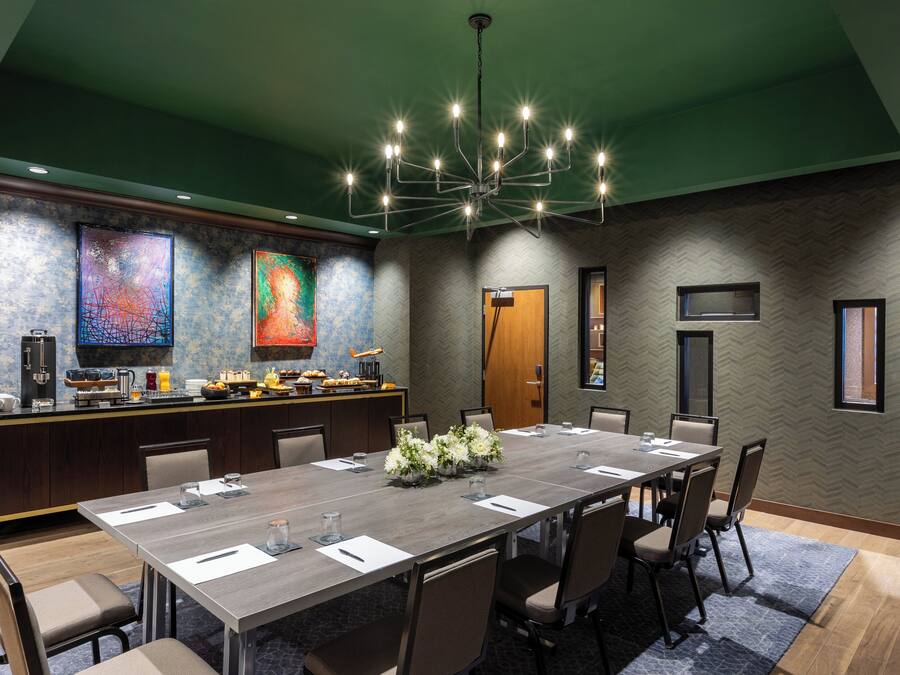 A conference room with a long table, chairs, a bar area, and artwork on the walls.