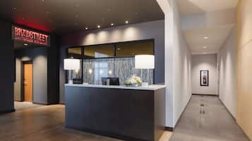 A reception desk with a modern design, a sign above it, and a hallway with a wooden floor and a framed picture on the wall.