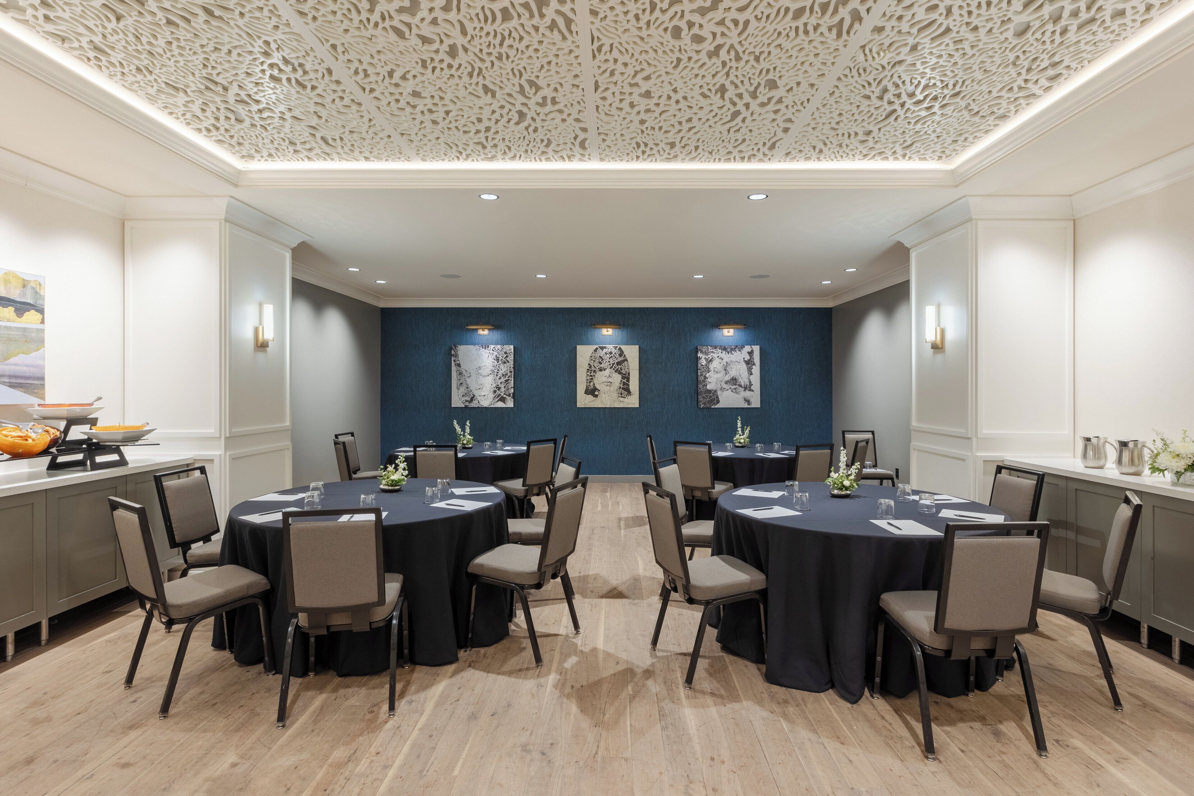 A conference room with round tables, chairs, and artwork on the walls.