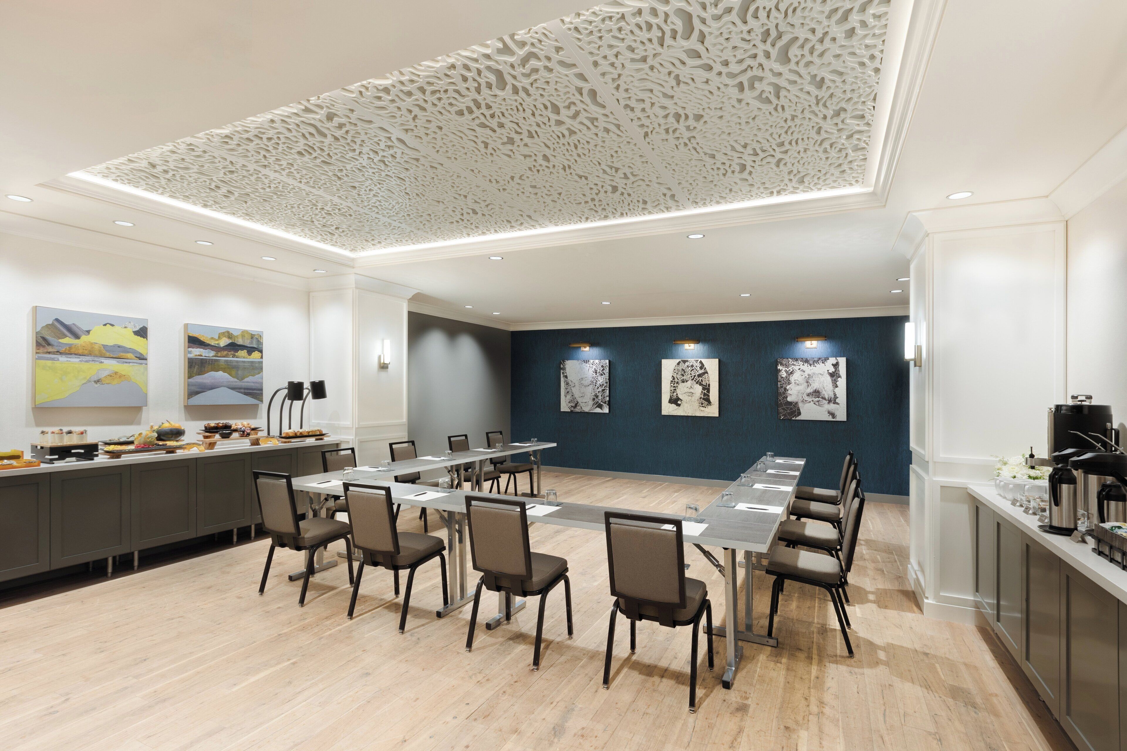 A conference room with a long table, chairs, and artwork on the walls.