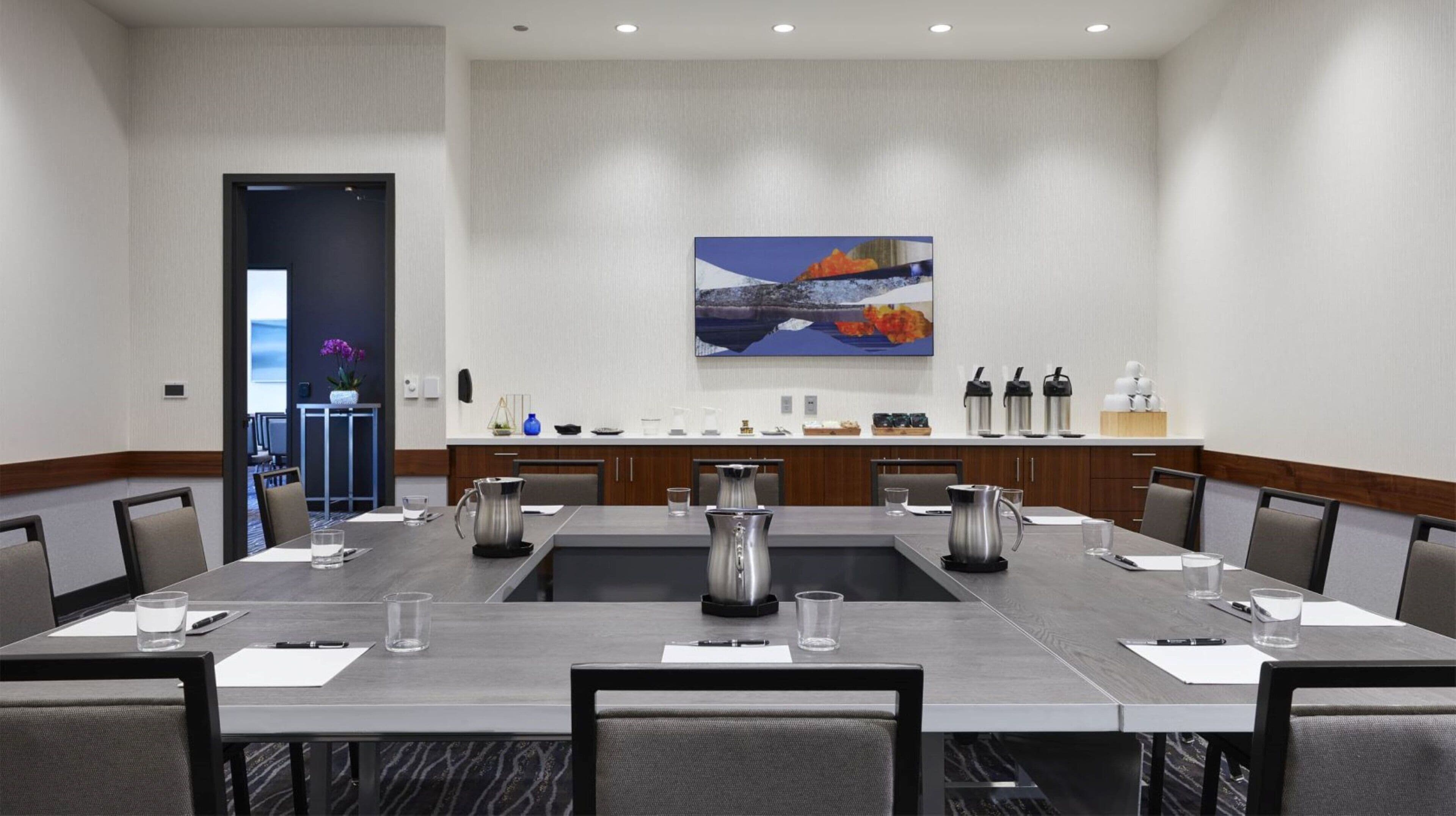 Une salle de conférence équipée d’une longue table, de chaises et d’un coin café.