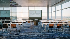 A conference room with a large screen displaying the InterContinental Hotels & Resorts logo, tables, chairs, and a carpeted floor. - InterContinental Minneapolis - St. Paul Airport by IHG (Minneapolis)