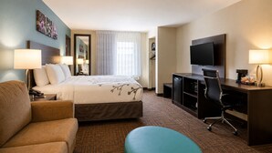 A hotel room with a bed, a desk, a chair, a sofa, and a television. - Sleep Inn & Suites Houston Westchase - Little Saigon (Houston)