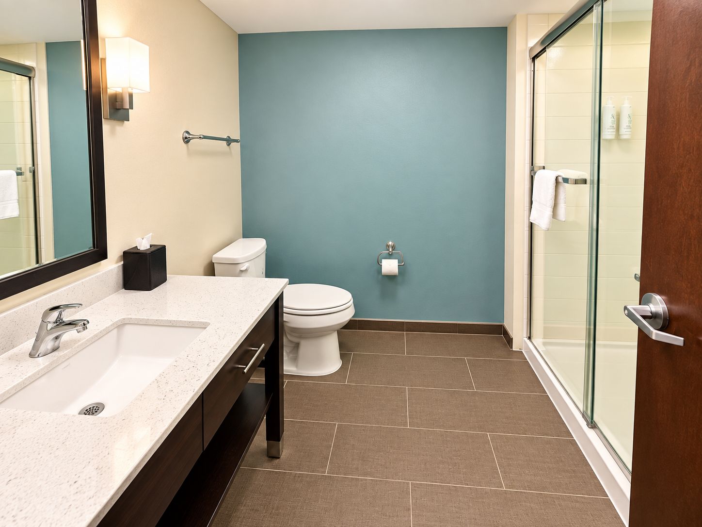 Ein modernes Badezimmer mit einem weißen Waschbecken, einer Toilette und einer Duschkabine aus Glas.