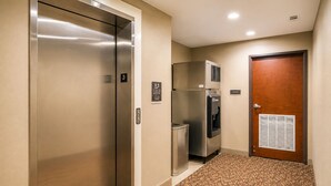A hallway with an elevator, a water cooler, and a storage room door. - Sleep Inn & Suites Houston Westchase - Little Saigon (Houston)