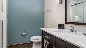A bathroom with a white toilet, a sink with a mirror, and a towel rack. - Sleep Inn & Suites Houston Westchase - Little Saigon (Houston)