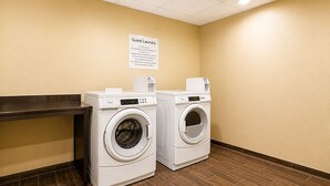 A hotel laundry room with two front-loading washing machines and a sign above them. - Sleep Inn & Suites Houston Westchase - Little Saigon (Houston)