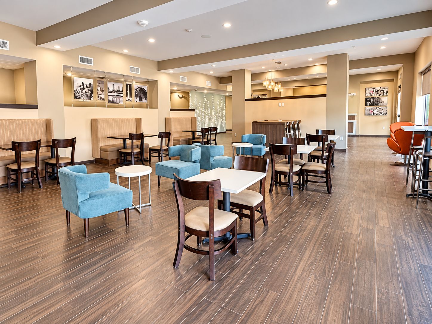 A modern dining area with booths and tables, wooden flooring, and artwork on the walls.