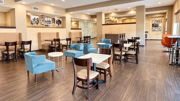 A modern dining area with booths and tables, wooden flooring, and artwork on the walls.