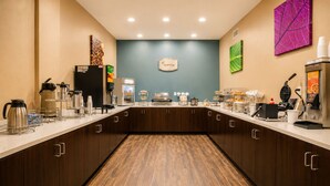 A hotel kitchen with a breakfast bar, coffee machines, and a clock on the wall. - Sleep Inn & Suites Houston Westchase - Little Saigon (Houston)