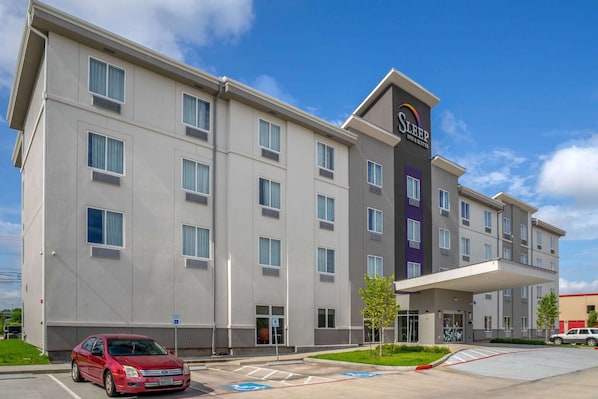 A multi-story hotel with a modern design, featuring a prominent entrance and a parking area. - Sleep Inn & Suites Houston Westchase - Little Saigon (Houston)