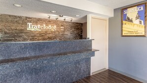 En receptionsdisk med en vägg av sten som bakgrund och en skylt med texten ”Travelodge”.