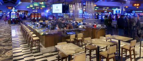 Um bar de casino com várias máquinas de jogo, área de bar e lugares para clientes.