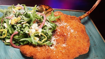A plate with a breaded cutlet, salad, and grilled vegetables.