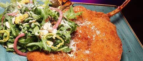 A plate with a breaded cutlet, salad, and grilled vegetables.
