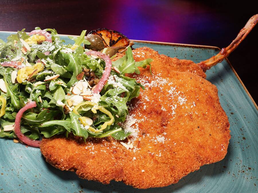 A plate with a breaded cutlet, salad, and grilled vegetables.
