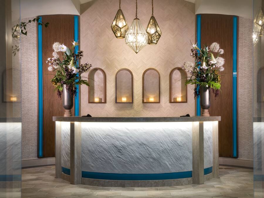 A reception area with a marble counter, decorative vases, wall-mounted lights, and a chandelier.