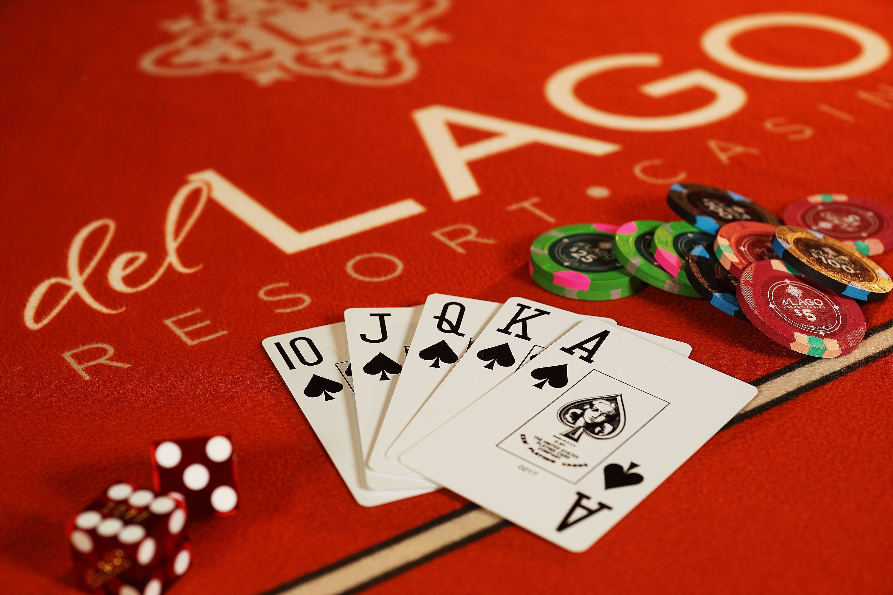 A red playing card table with a logo, poker chips, and playing cards.