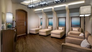 A room with a wooden door, a glass table with a lamp, and four sofas arranged in a semi-circle facing a large window with a view of the ocean. - del Lago Resort & Casino (Waterloo)