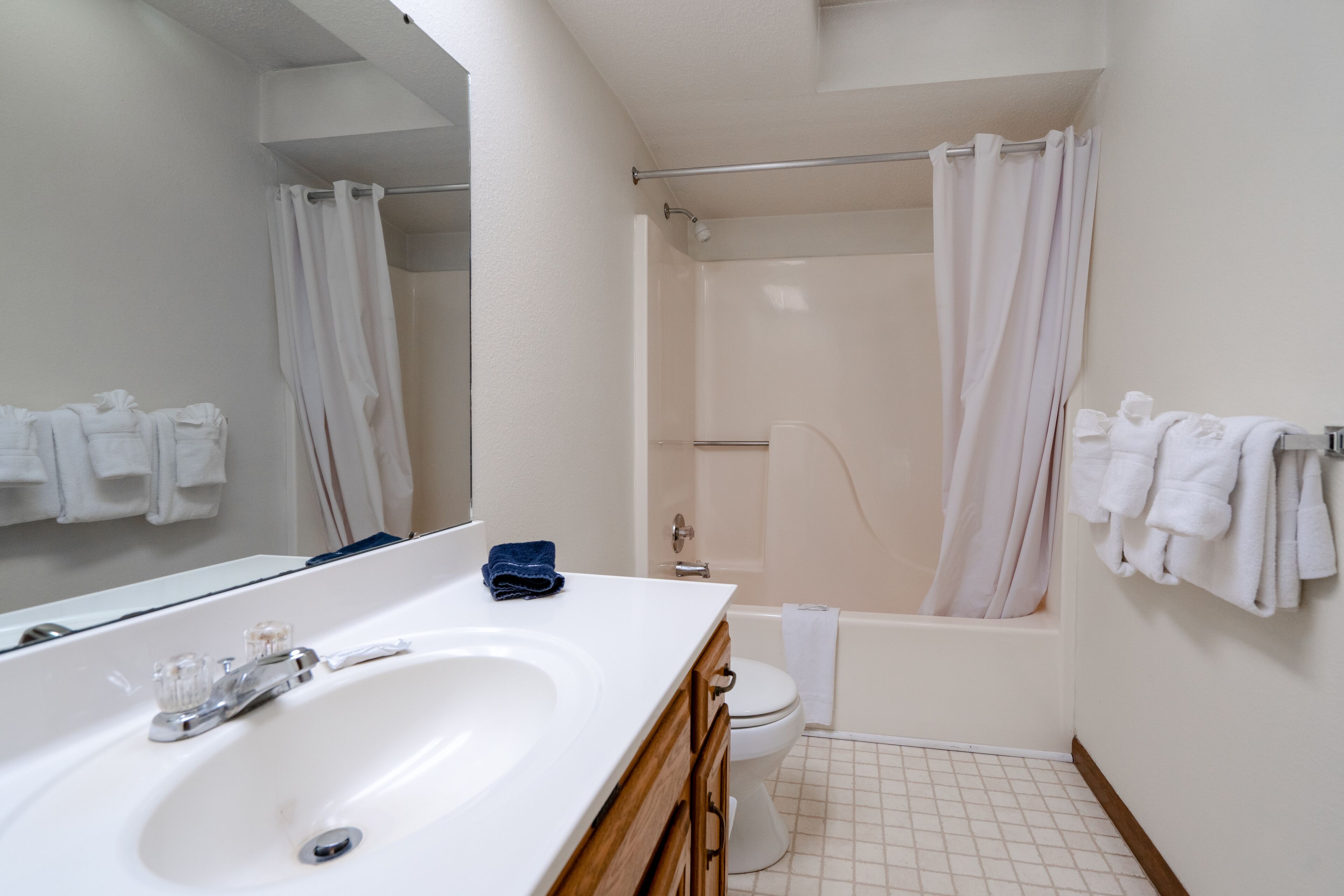 A bathroom with a white sink, mirror, and bathtub.