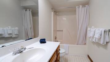 A bathroom with a white sink, mirror, and bathtub.